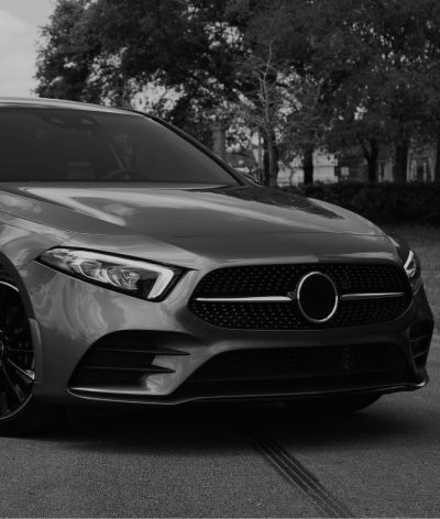 A black and white photo of a mercedes benz a class parked in a parking lot.