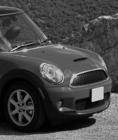 A black and white photo of a mini cooper parked on a dirt road. | InTown Auto Care