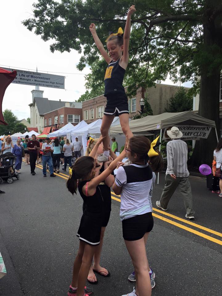 A cheerleader is being lifted in the air by two other girls. | InTown Auto Care