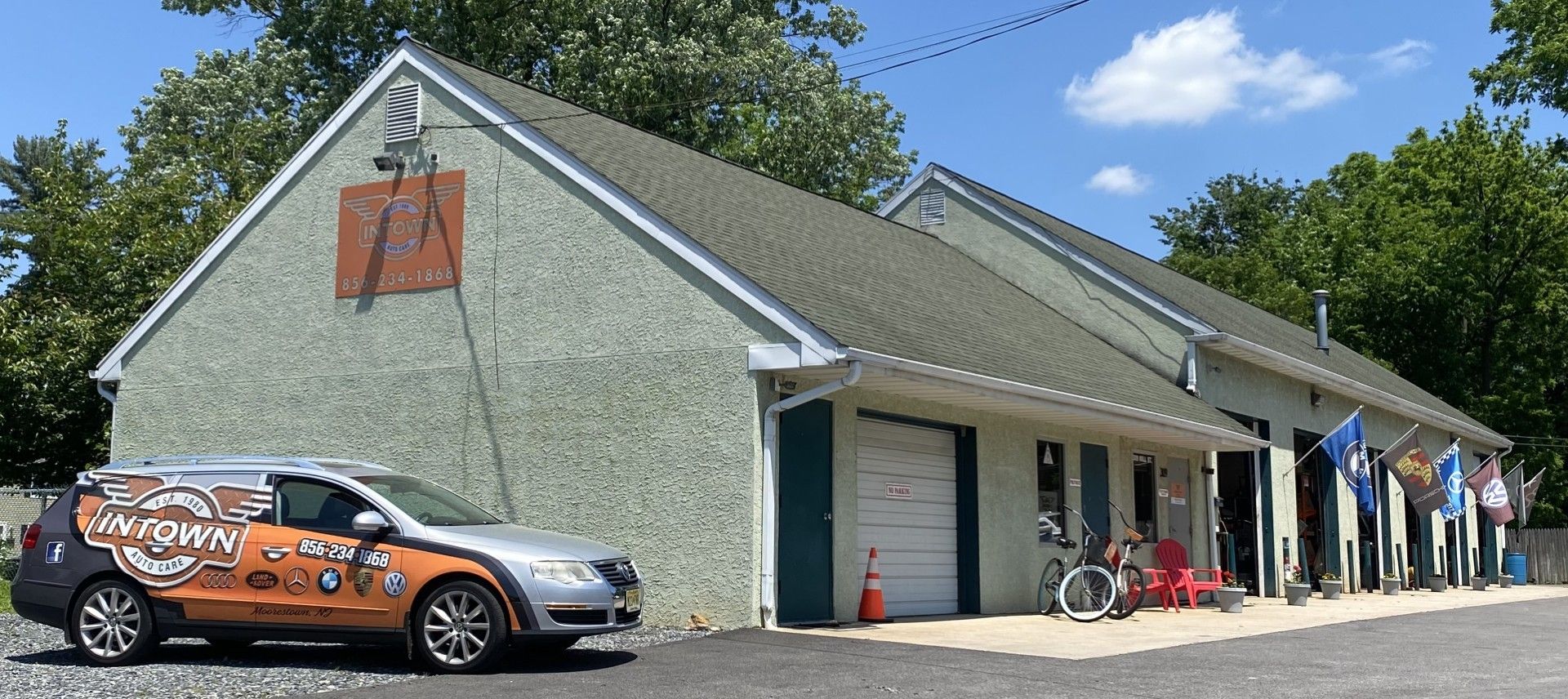 An orange van is parked in front of a building. | InTown Auto Care