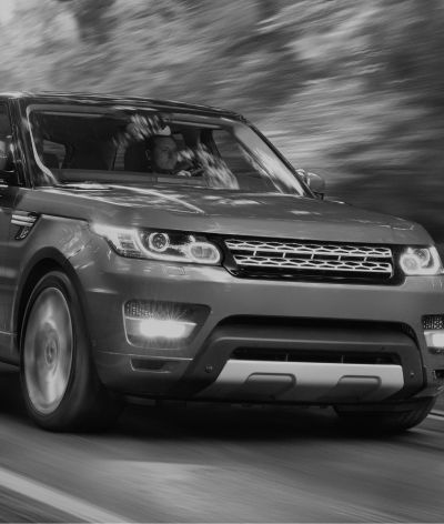 A black and white photo of a range rover sport driving down a road. | InTown Auto Care