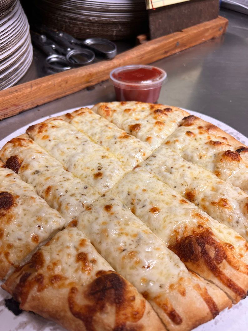 A close up of a cheese stick pizza on a plate.
