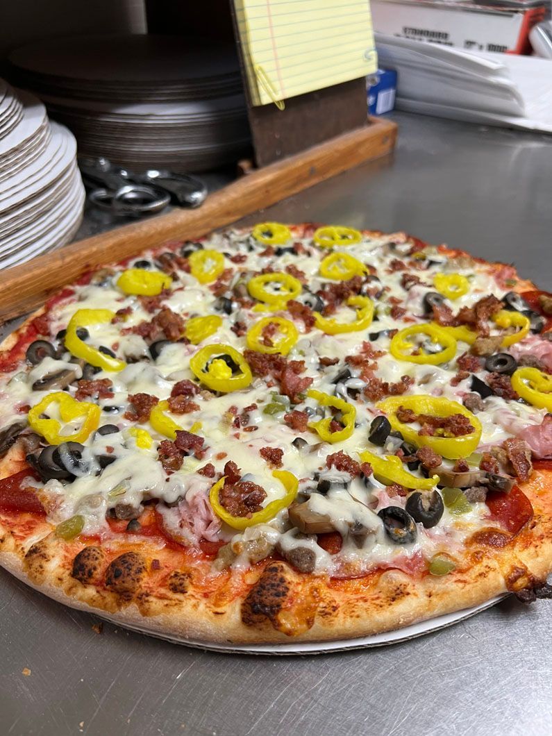 A pizza with a lot of toppings on it is sitting on a table.