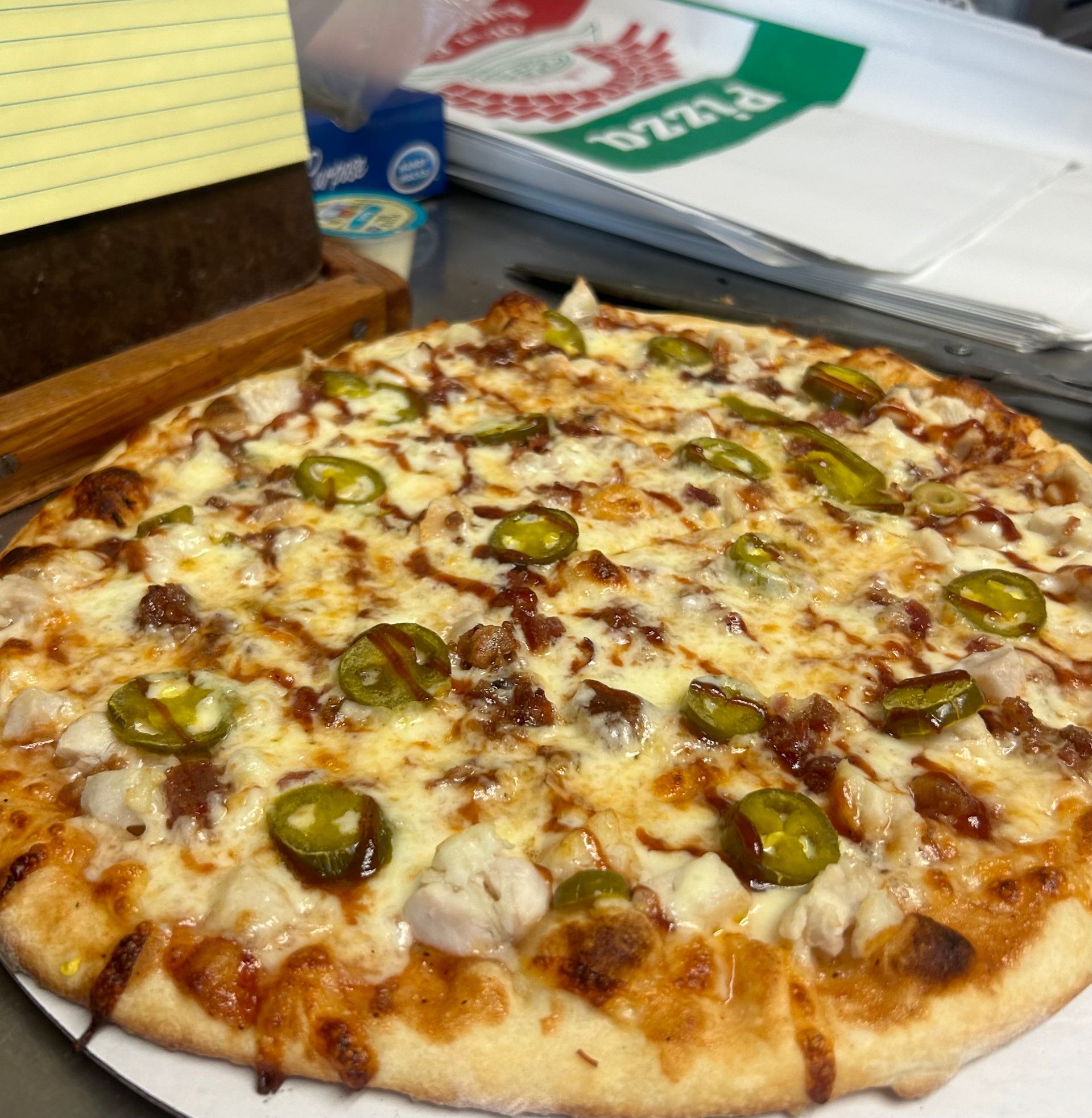 A pizza with jalapenos and cheese on a white plate