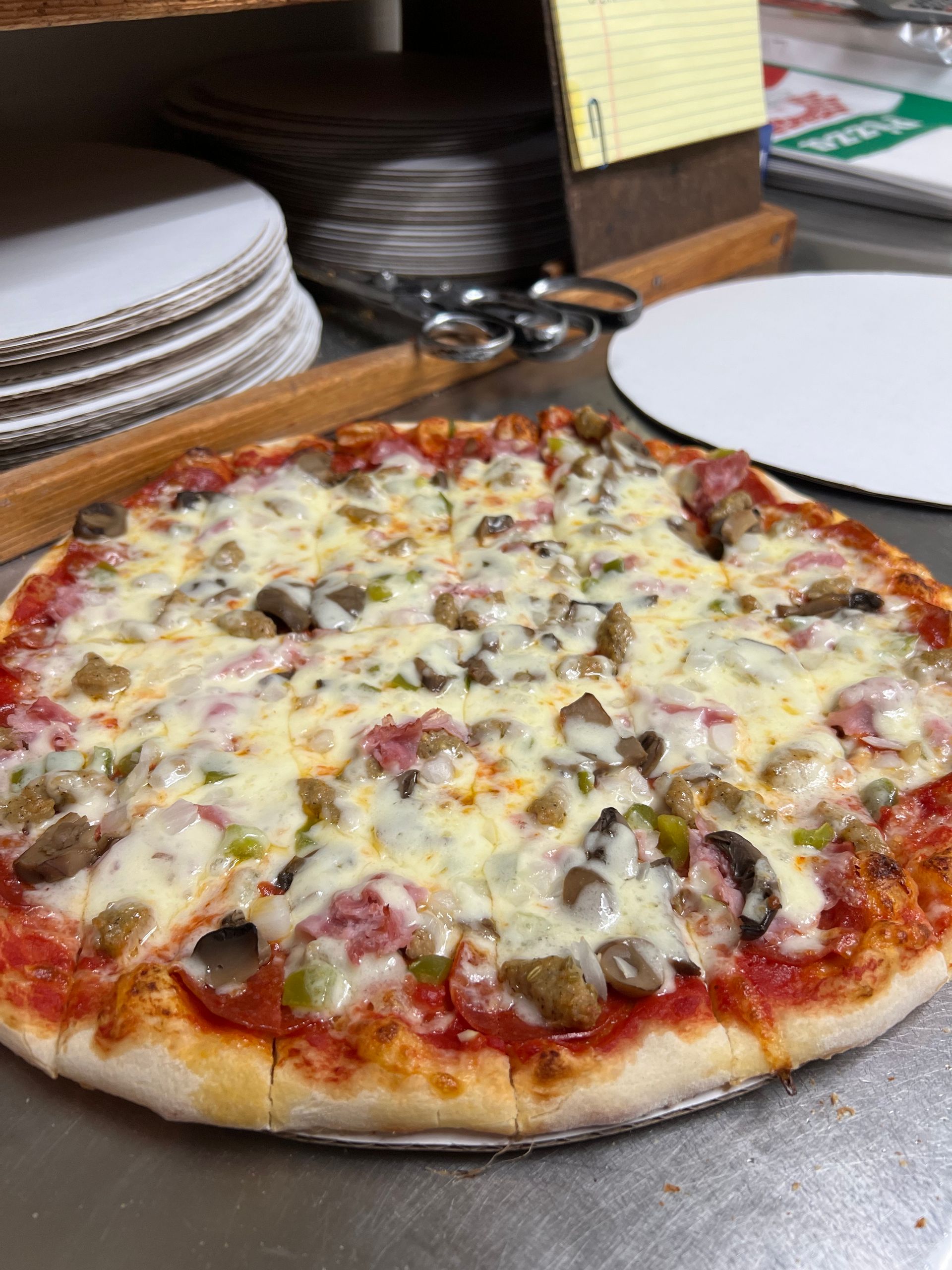 A pizza with a lot of toppings is sitting on a table.