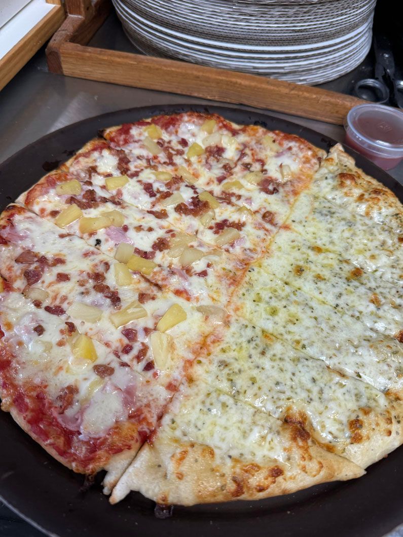 A pizza with four different toppings is on a plate.