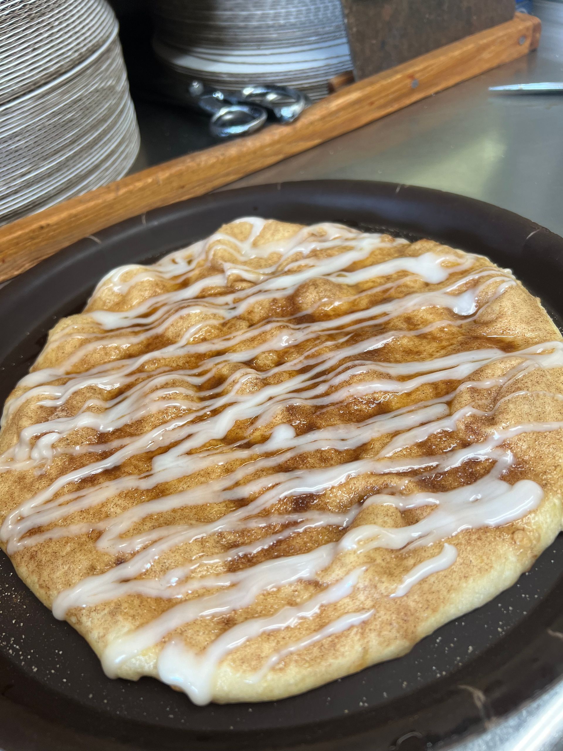 A cinnamon roll with icing on it is on a plate.