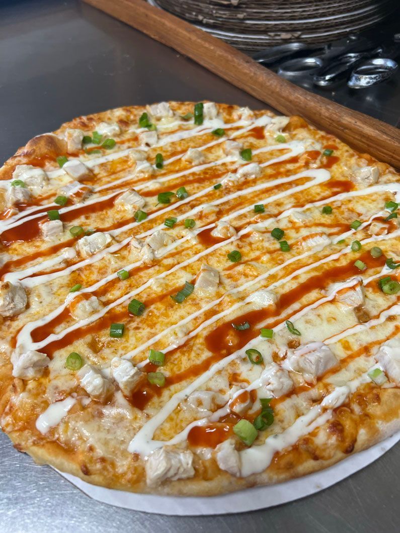 A pizza with sauce and onions on it is sitting on a table.