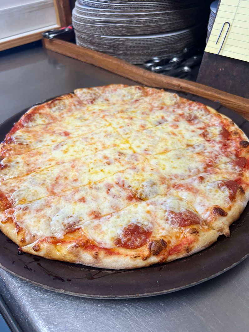 A pizza is sitting on a pan on a table.