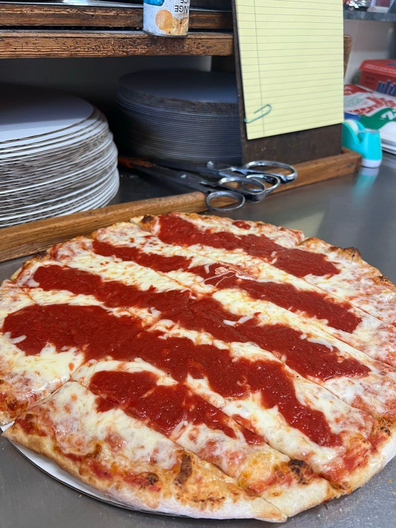 A pizza with tomato sauce on it is sitting on a counter.