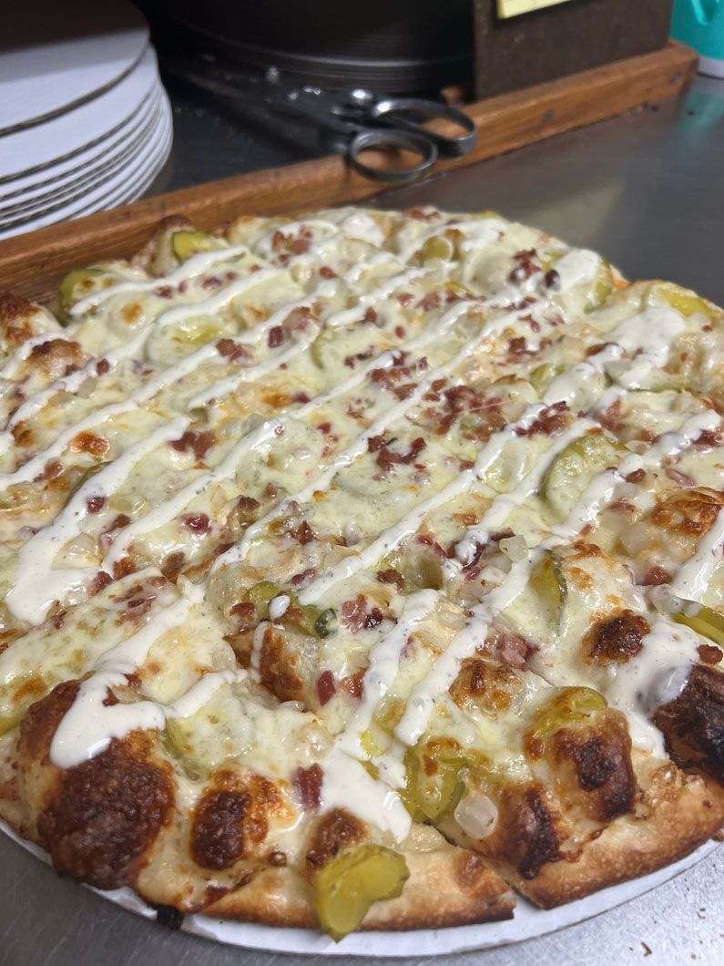 A pizza with a lot of toppings on it is on a plate on a table.