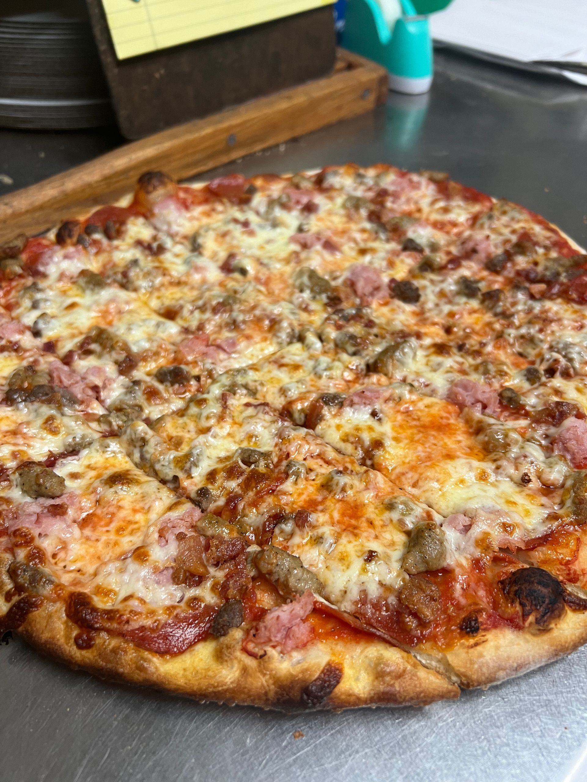 A pizza with a lot of toppings on it is sitting on a table.