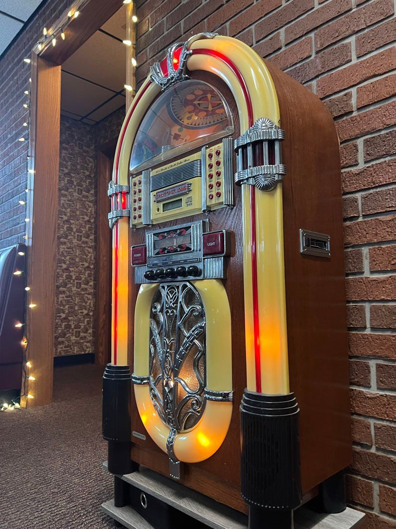 A jukebox is sitting in front of a brick wall.