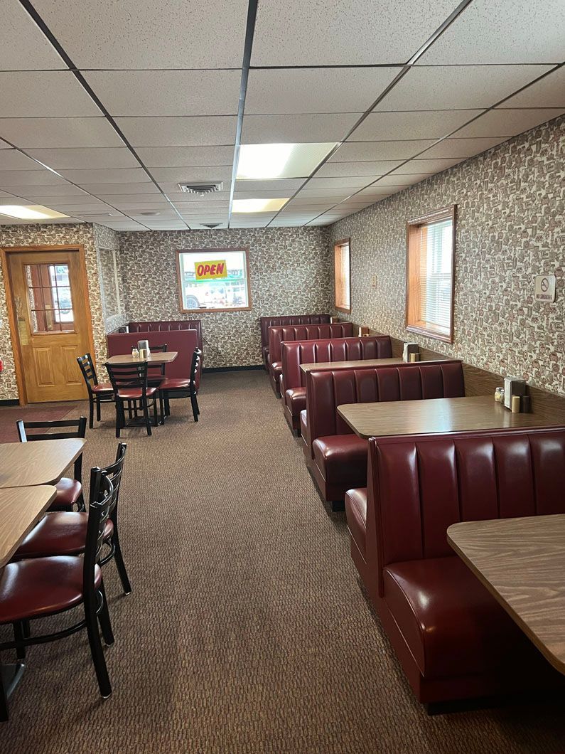 A restaurant filled with tables and red booths.