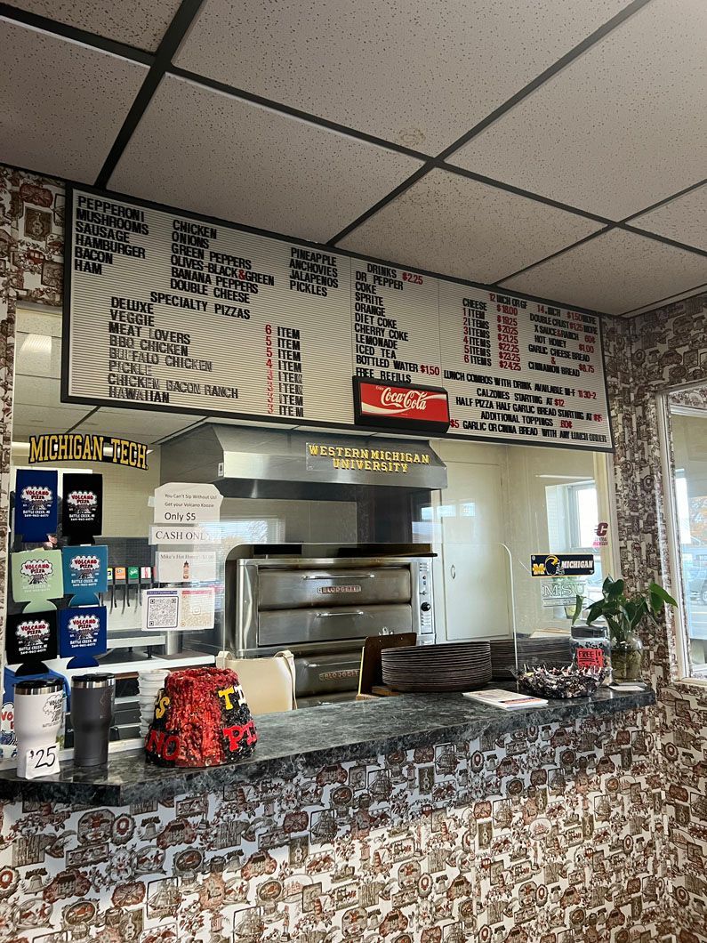 A pizza restaurant with a coca cola sign above the counter.