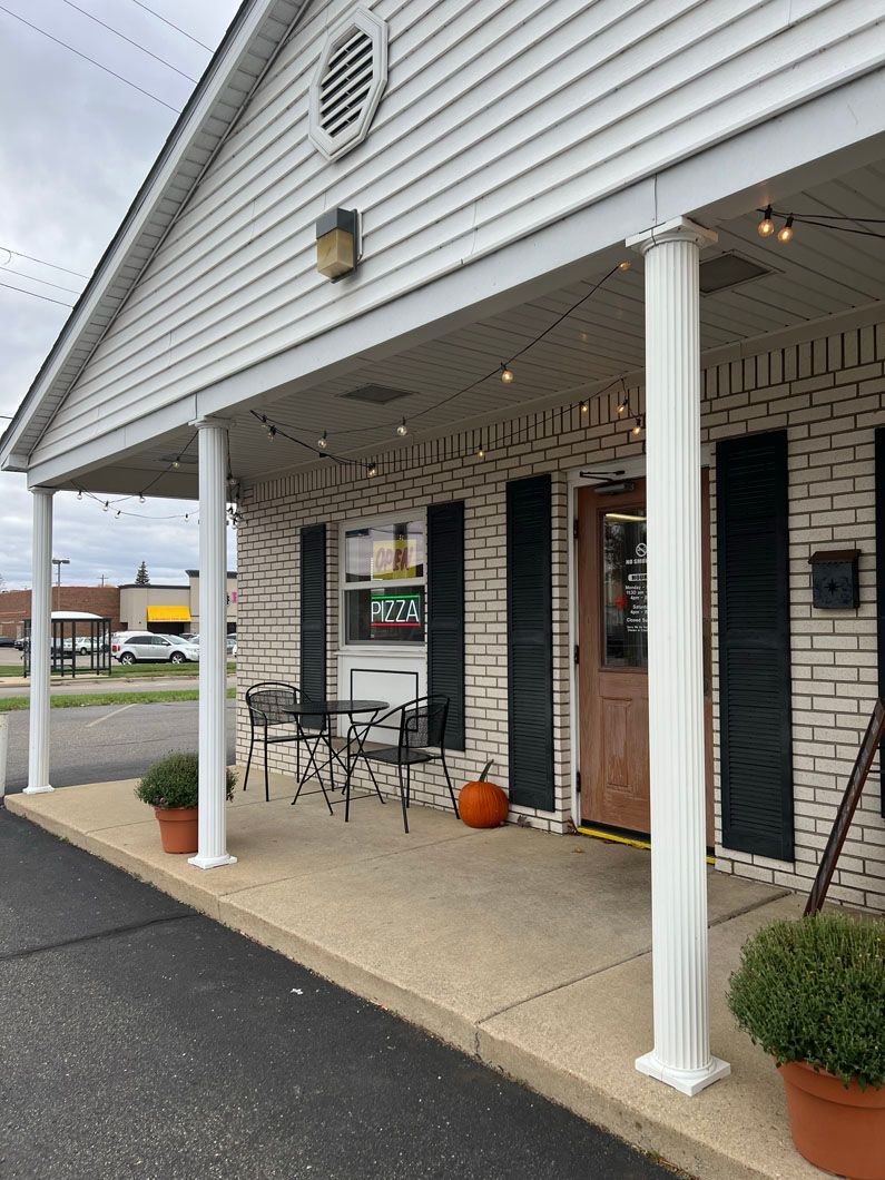 A white building with black shutters and a porch