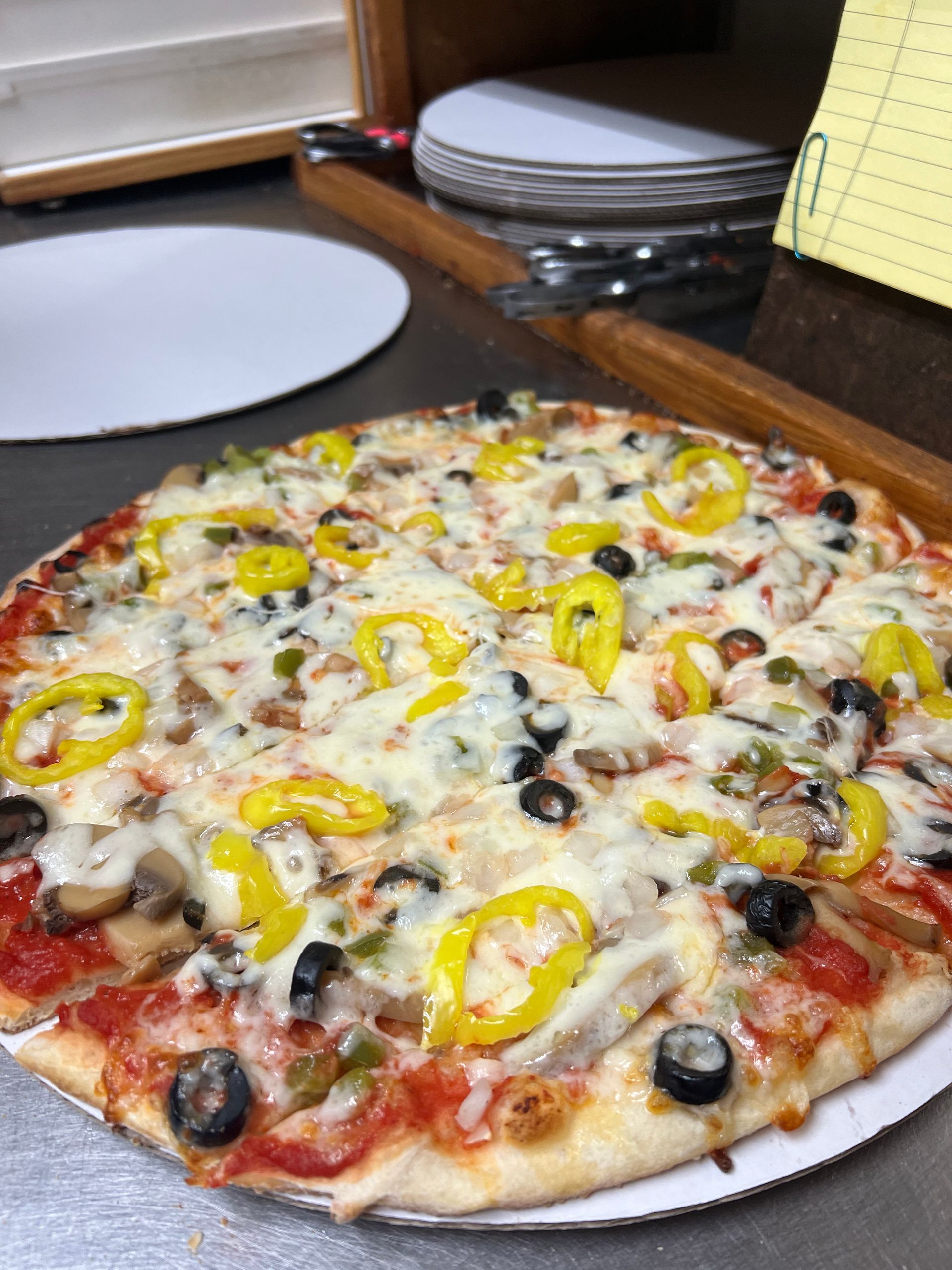 A pizza with a lot of toppings on it is sitting on a table.