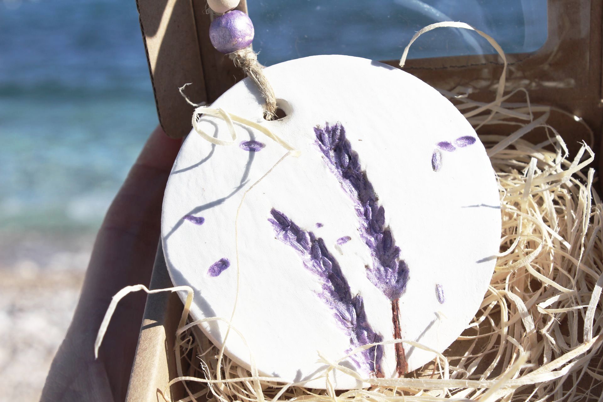 A person is holding a white circle with purple flowers on it.