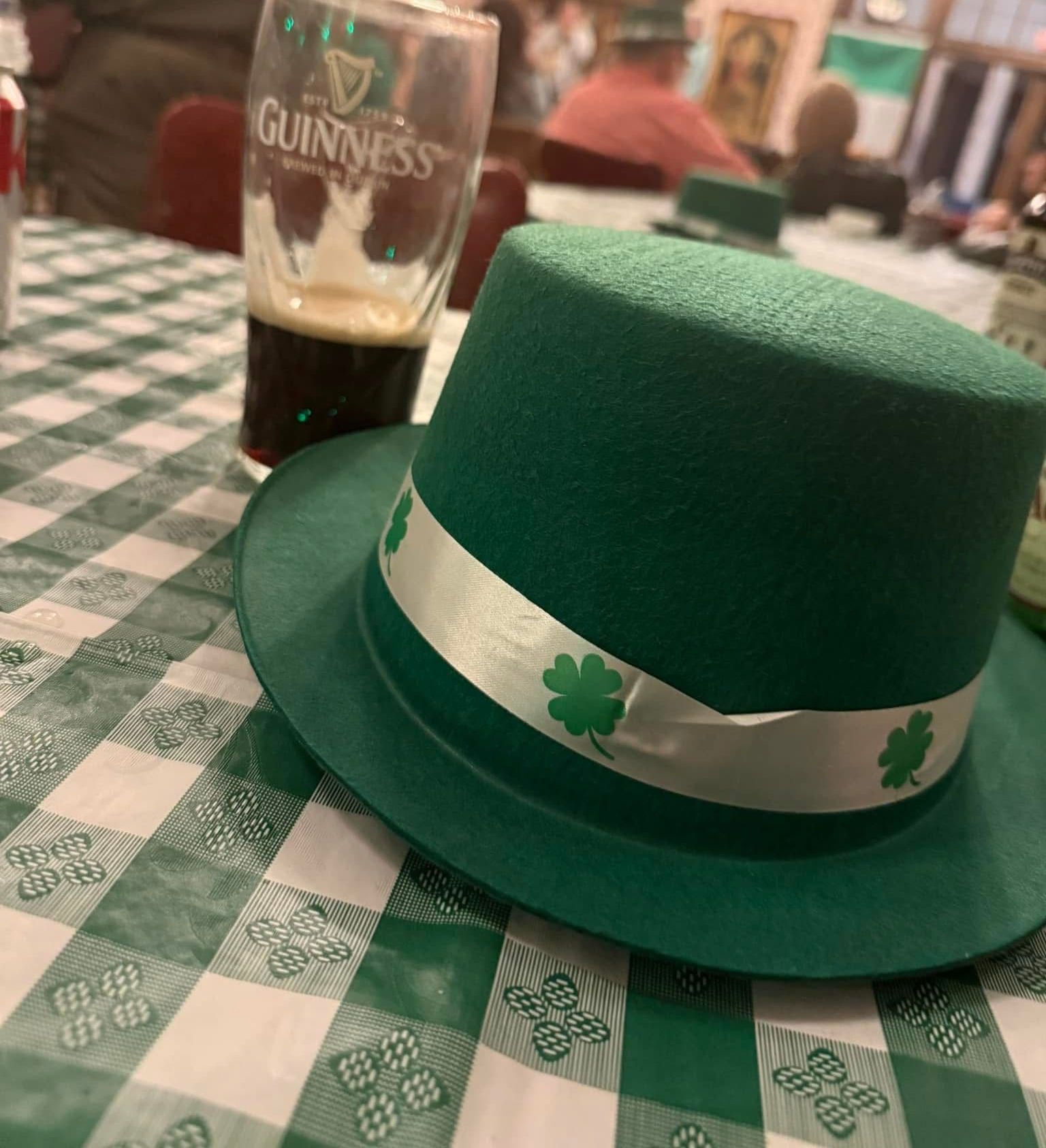 A woman with curly hair is wearing a tan coat and smiling.