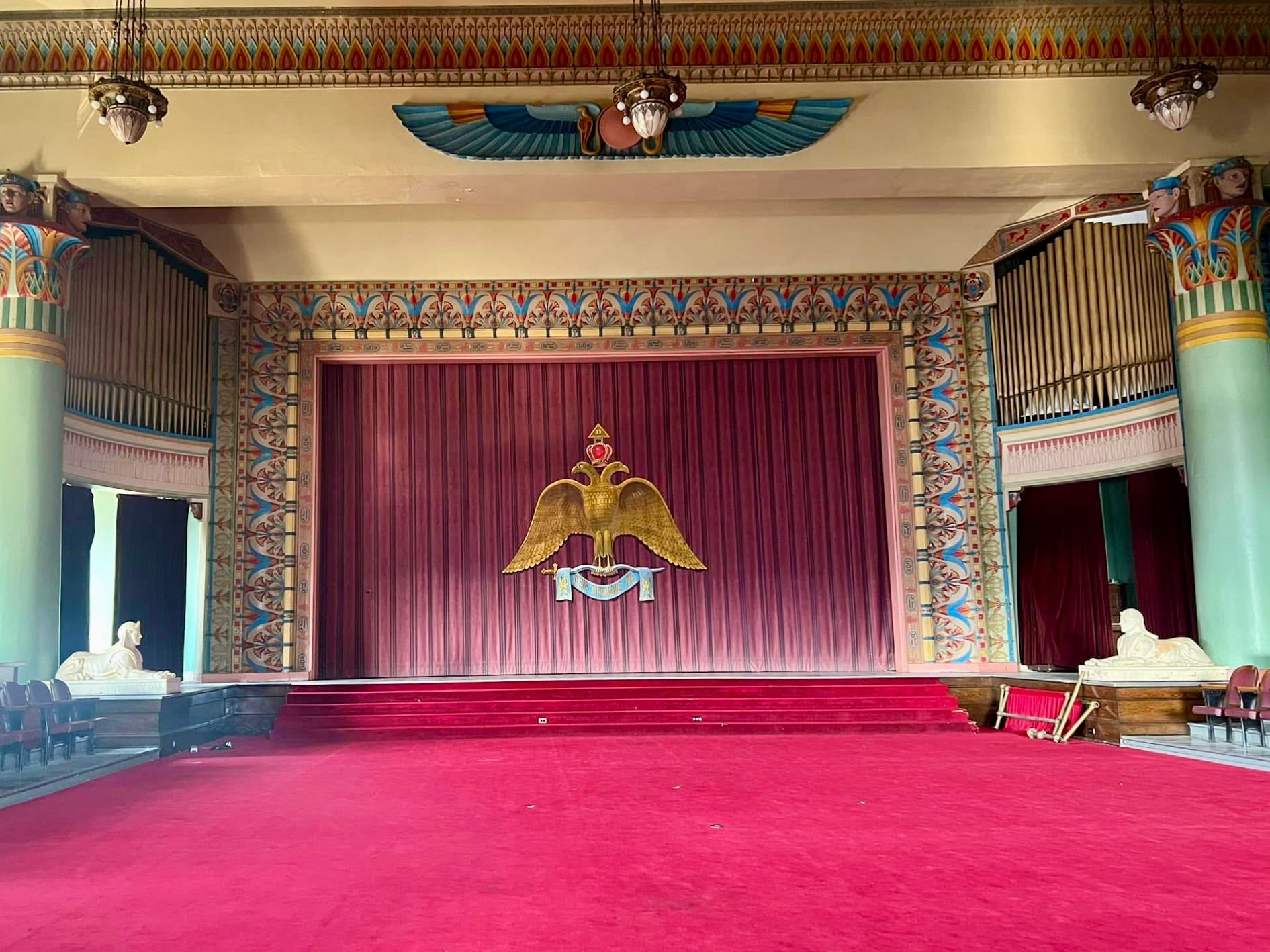 A large room with a red carpet and a stage with the Scottish Rite on it.