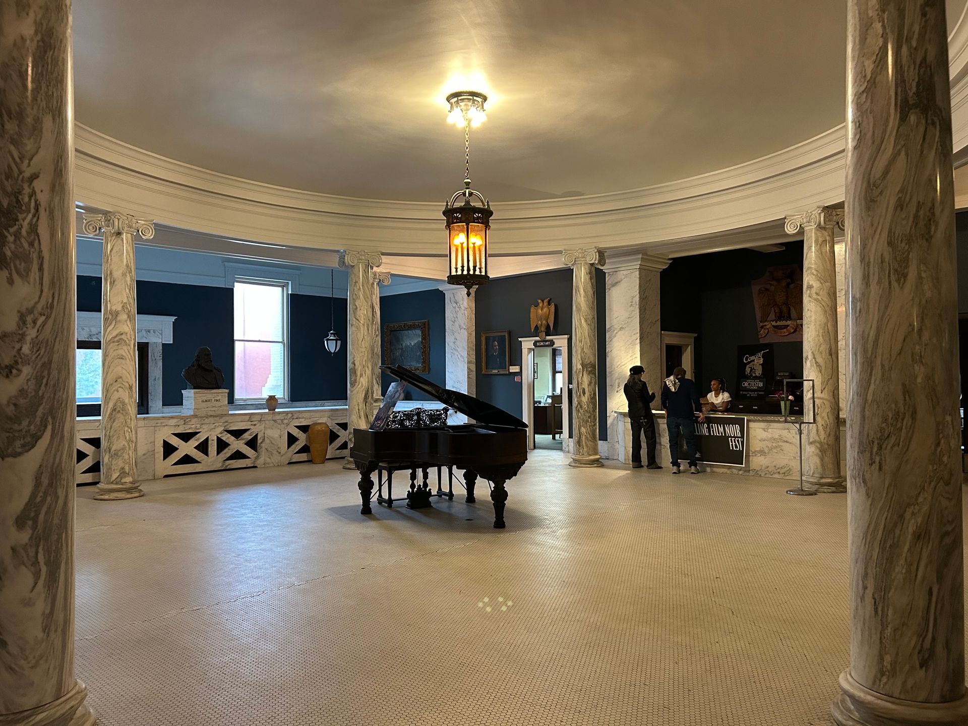 A grand piano is sitting in the middle of a large Rotunda with columns.