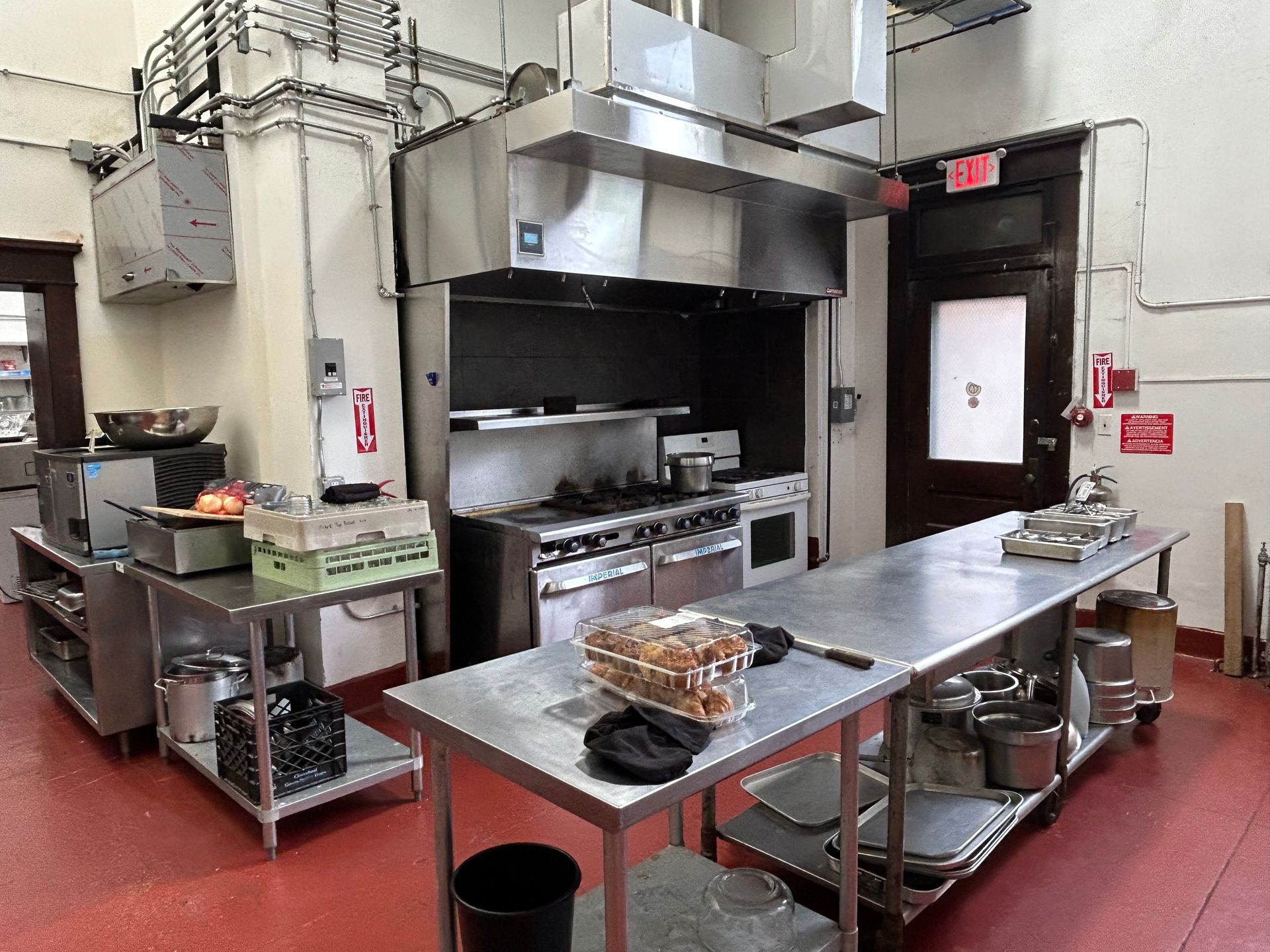 A kitchen with stainless steel appliances and a red floor.