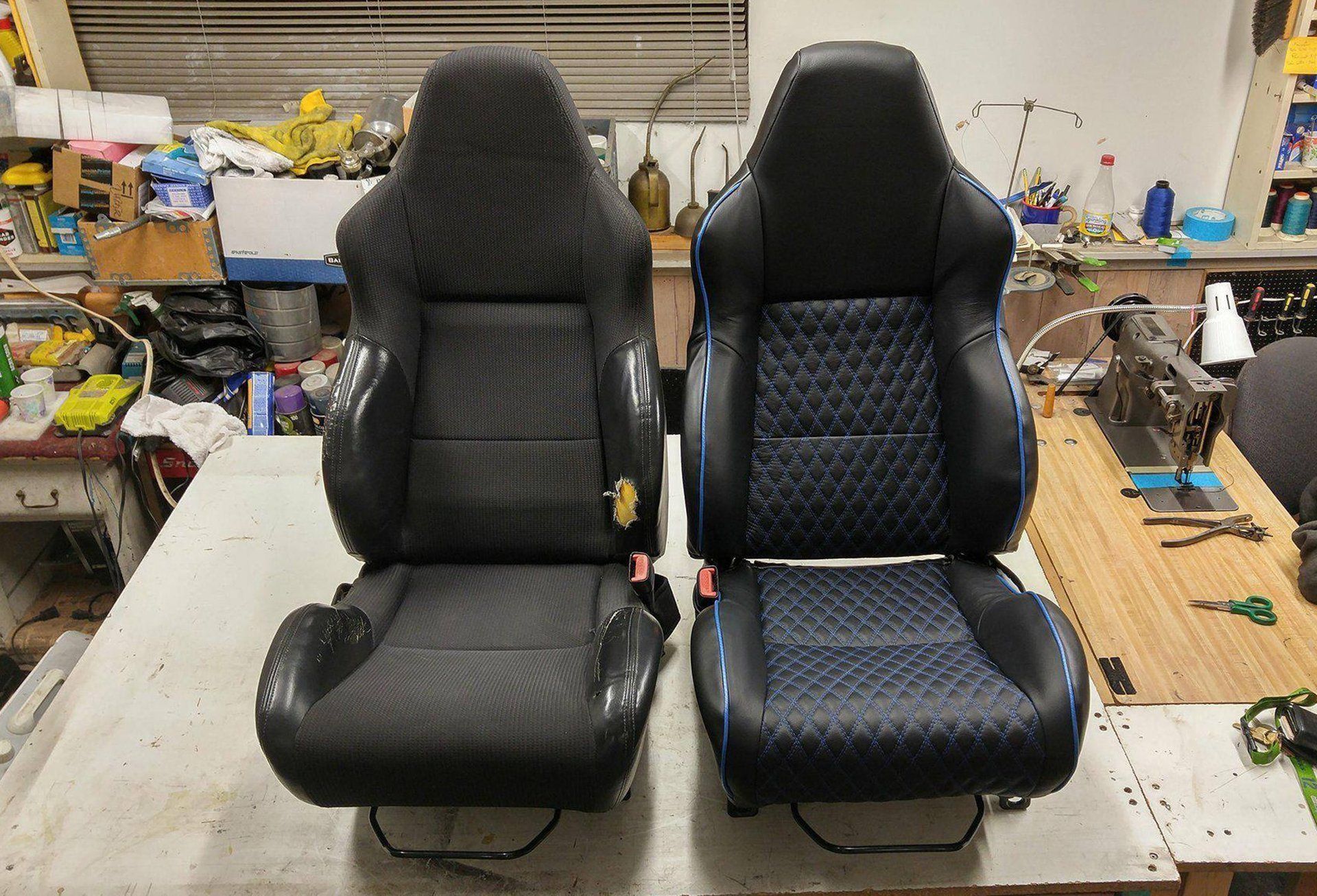 Two seats are sitting on a table in a garage.