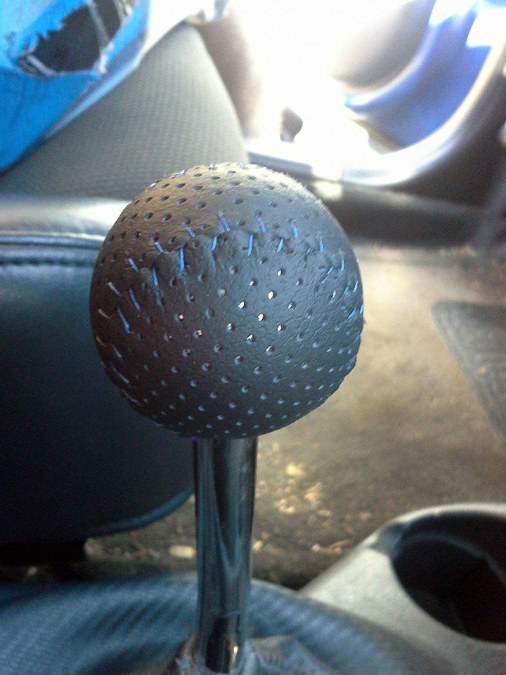 A close up of a black leather shift knob in a car