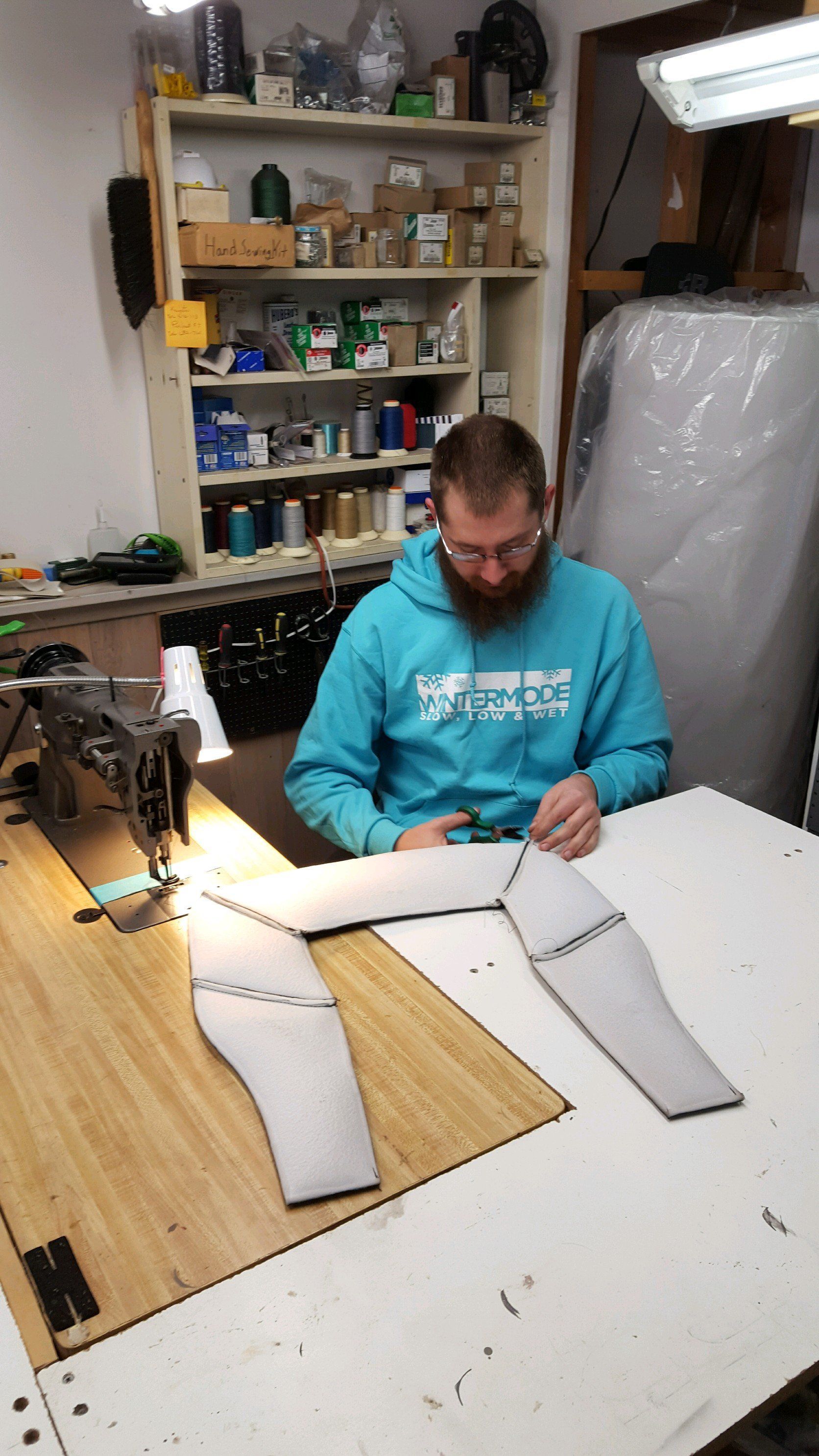 A man is sitting at a table using a sewing machine