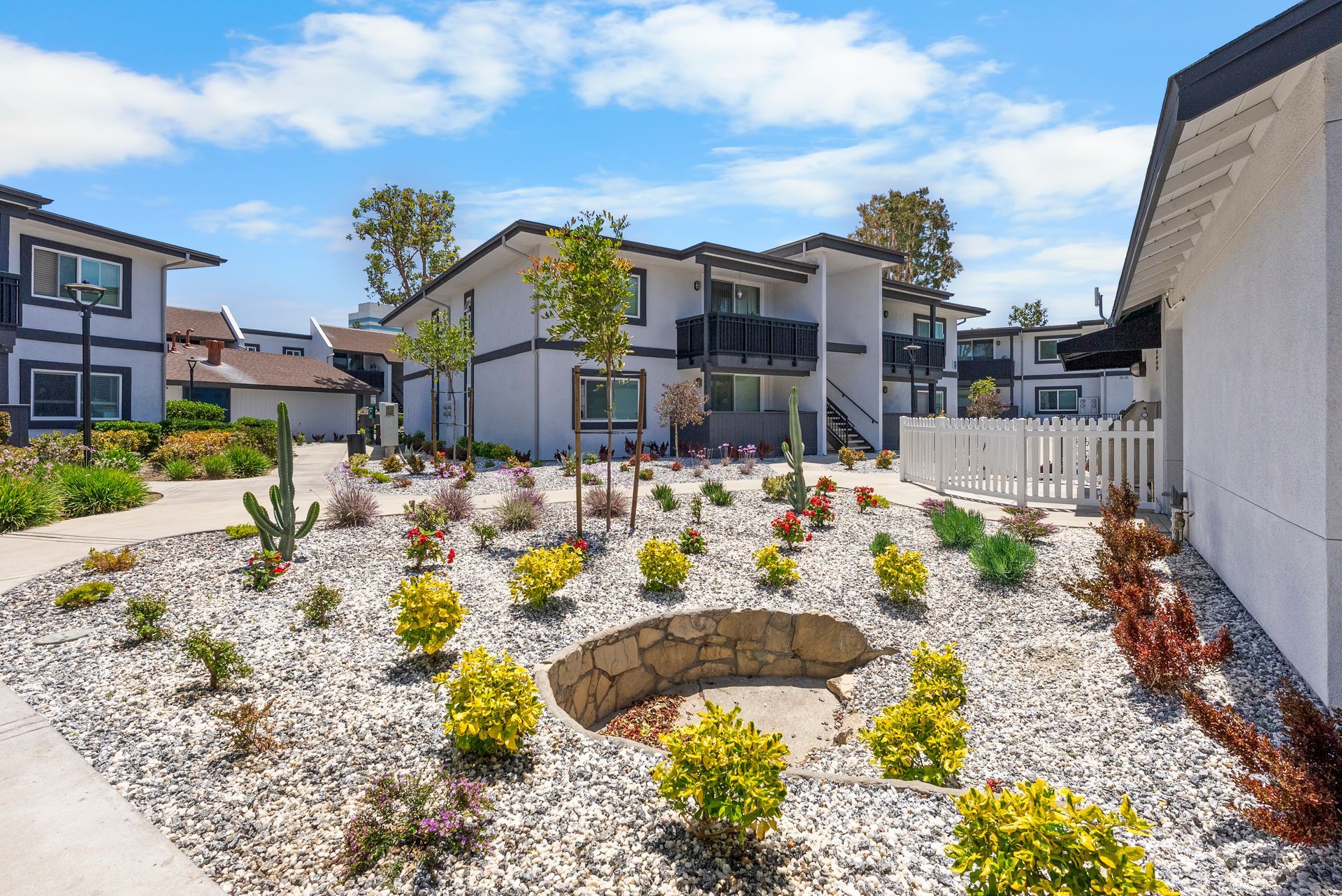 There is a pit in the middle of a garden in front of a building.