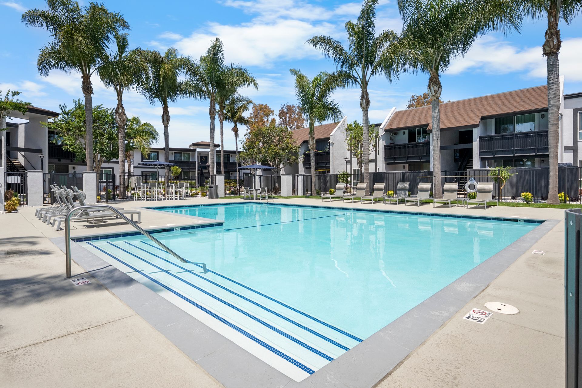 A large swimming pool surrounded by palm trees in front of a building.
