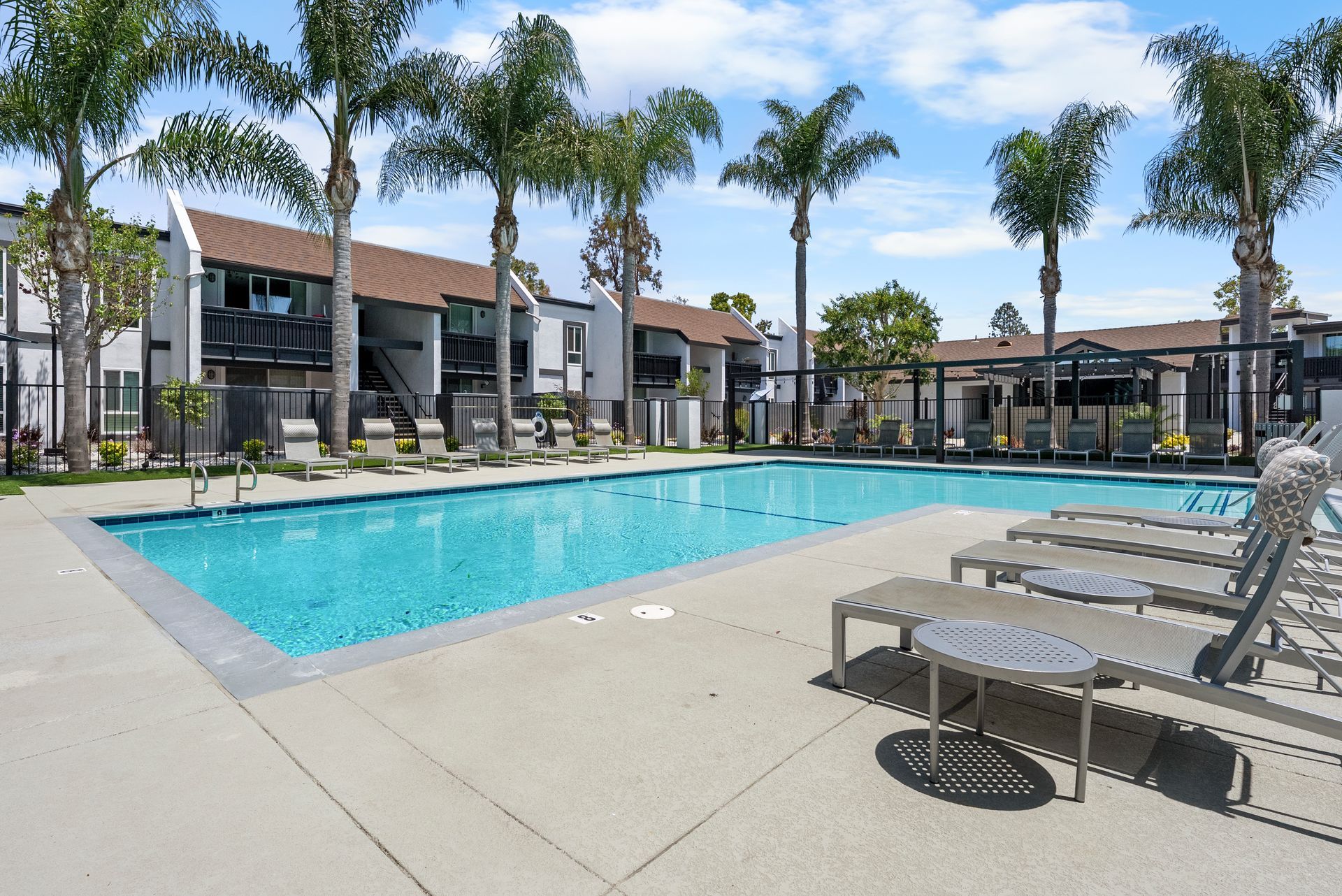 A large swimming pool in front of a building with palm trees