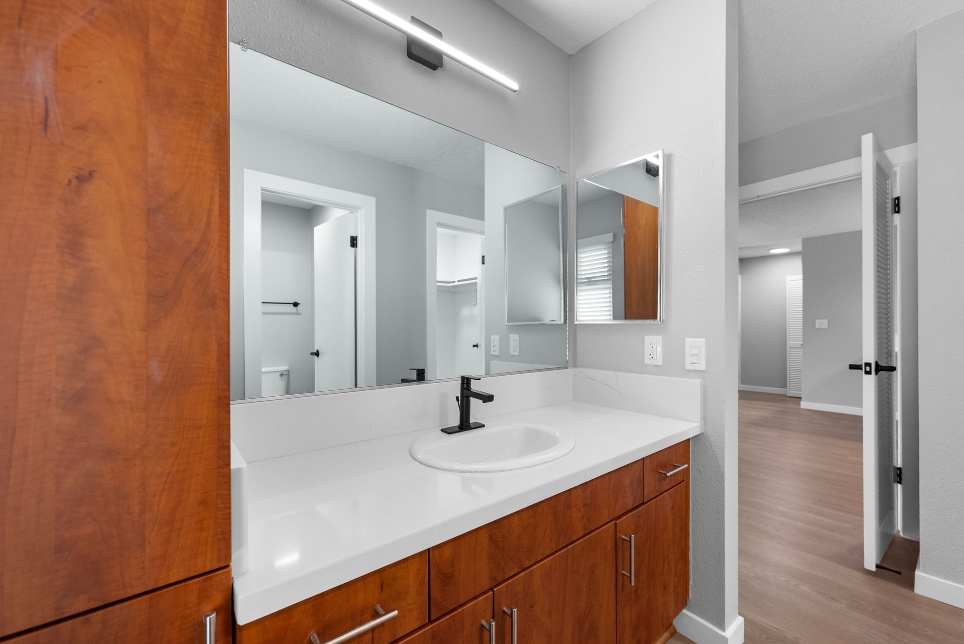 A bathroom with a sink , mirror and wooden cabinets.