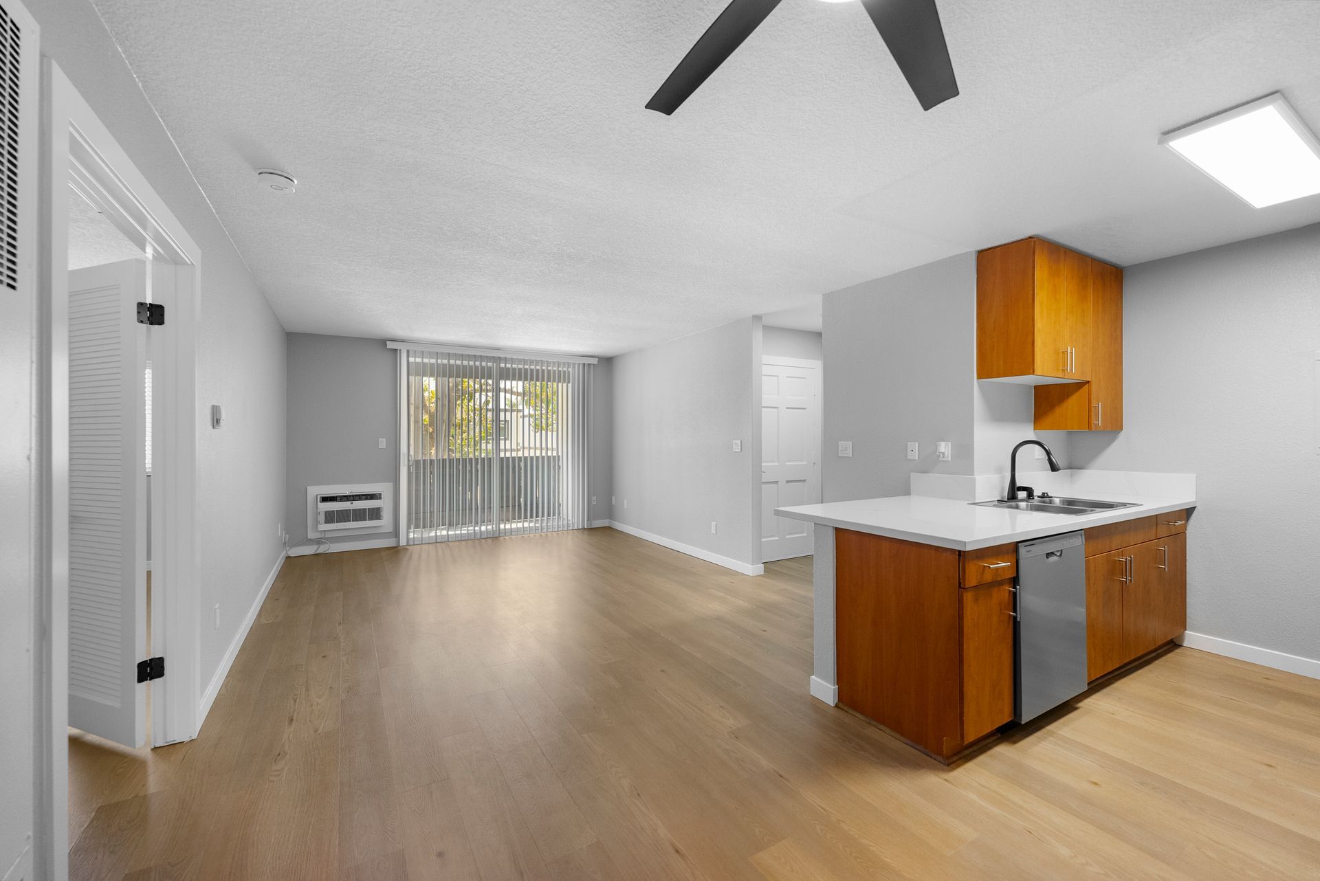 An empty apartment with a kitchen and a ceiling fan.