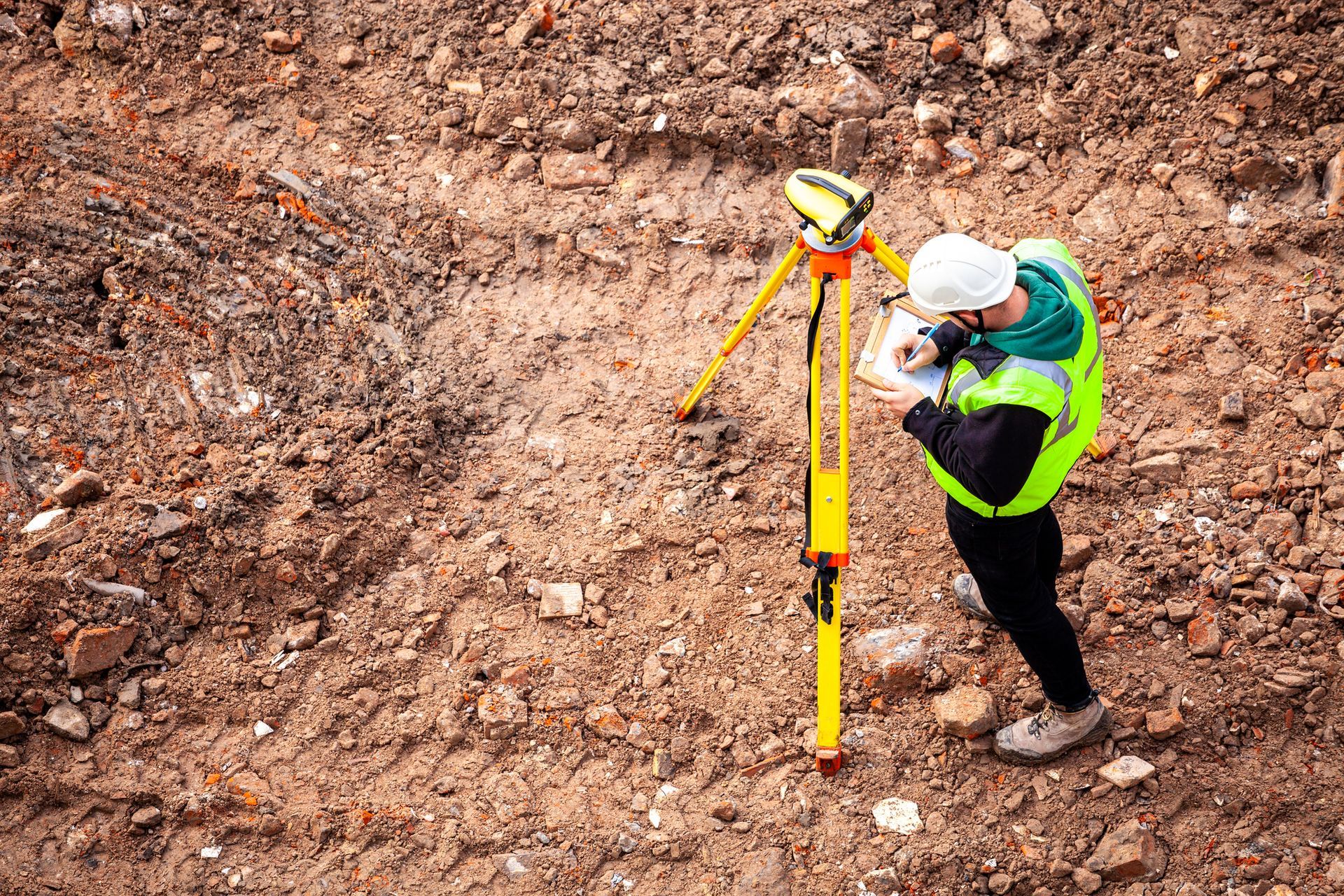A man is standing in the dirt next to a tripod.