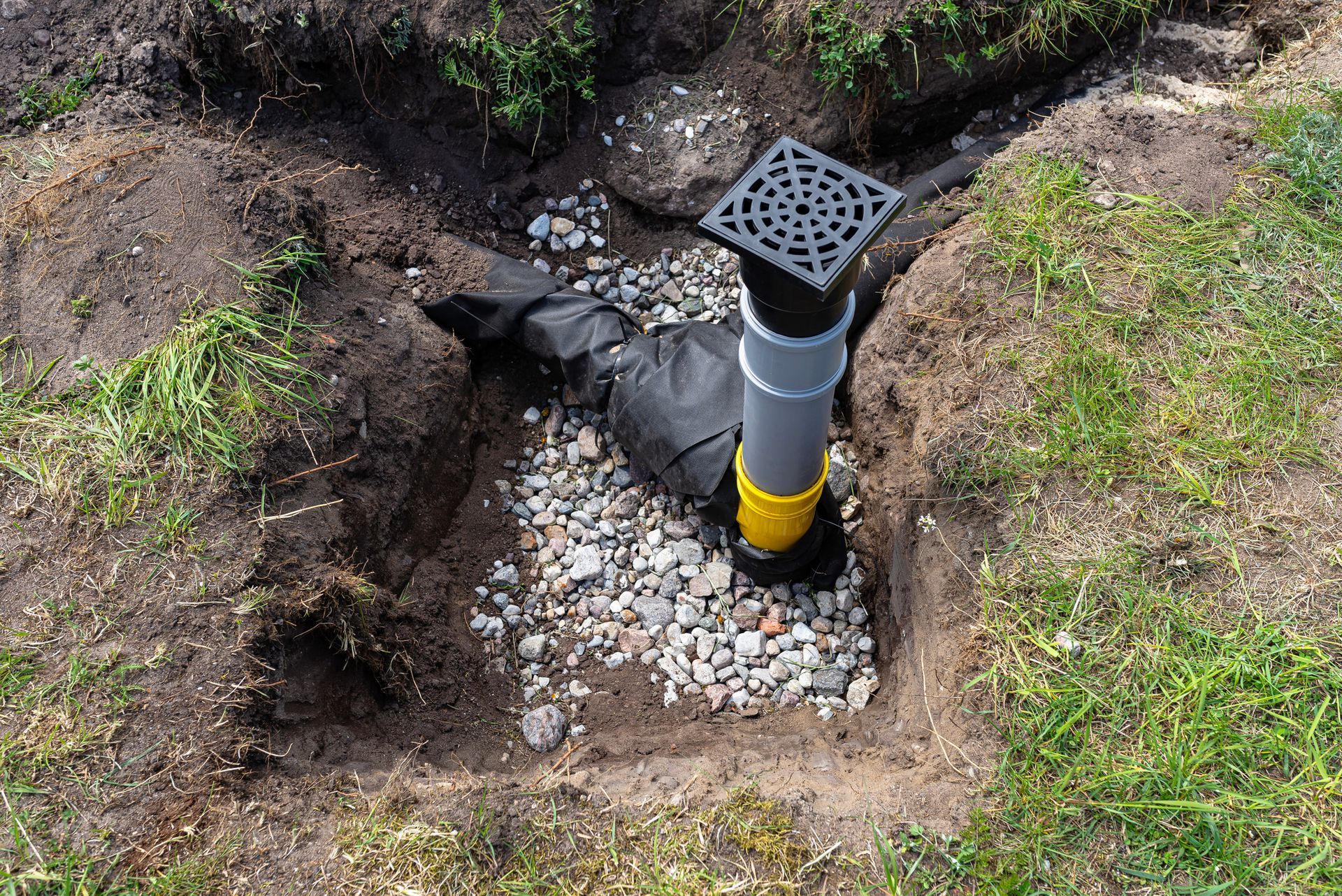 A drain pipe is being installed in a hole in the ground.