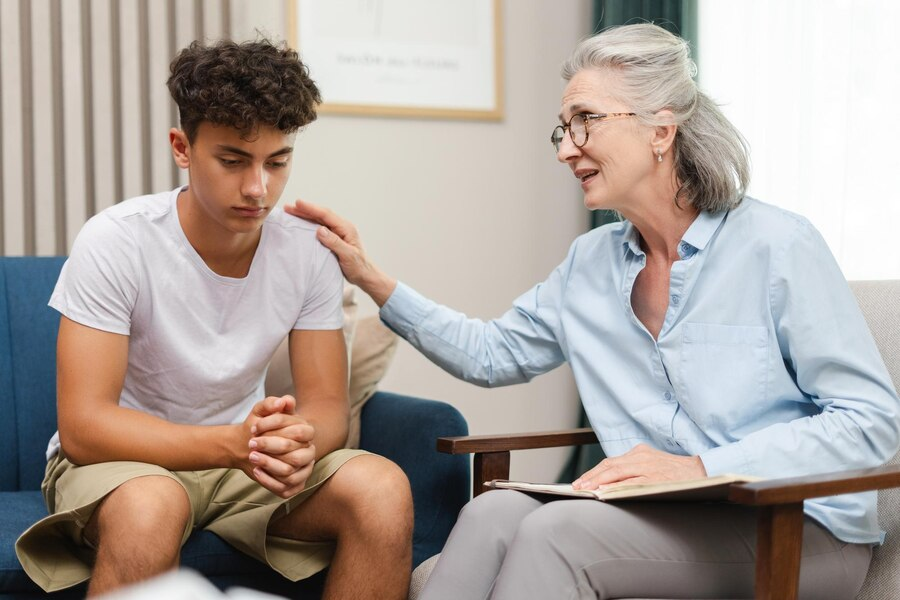 A woman is talking to a young man while sitting on a couch.