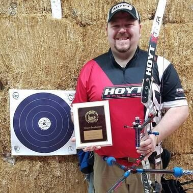 A man holding an award and a bow.
