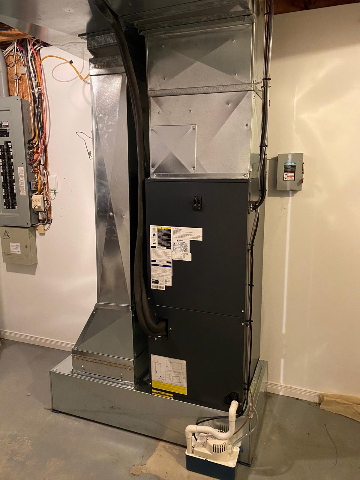 Un grand climatiseur se trouve dans un sous-sol à côté d'un mur.