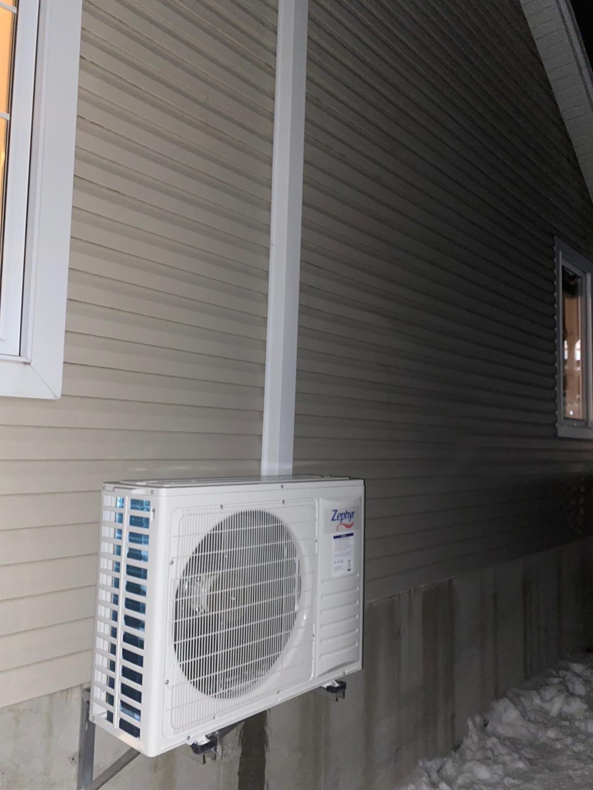 Un climatiseur blanc est monté sur le côté d'une maison.