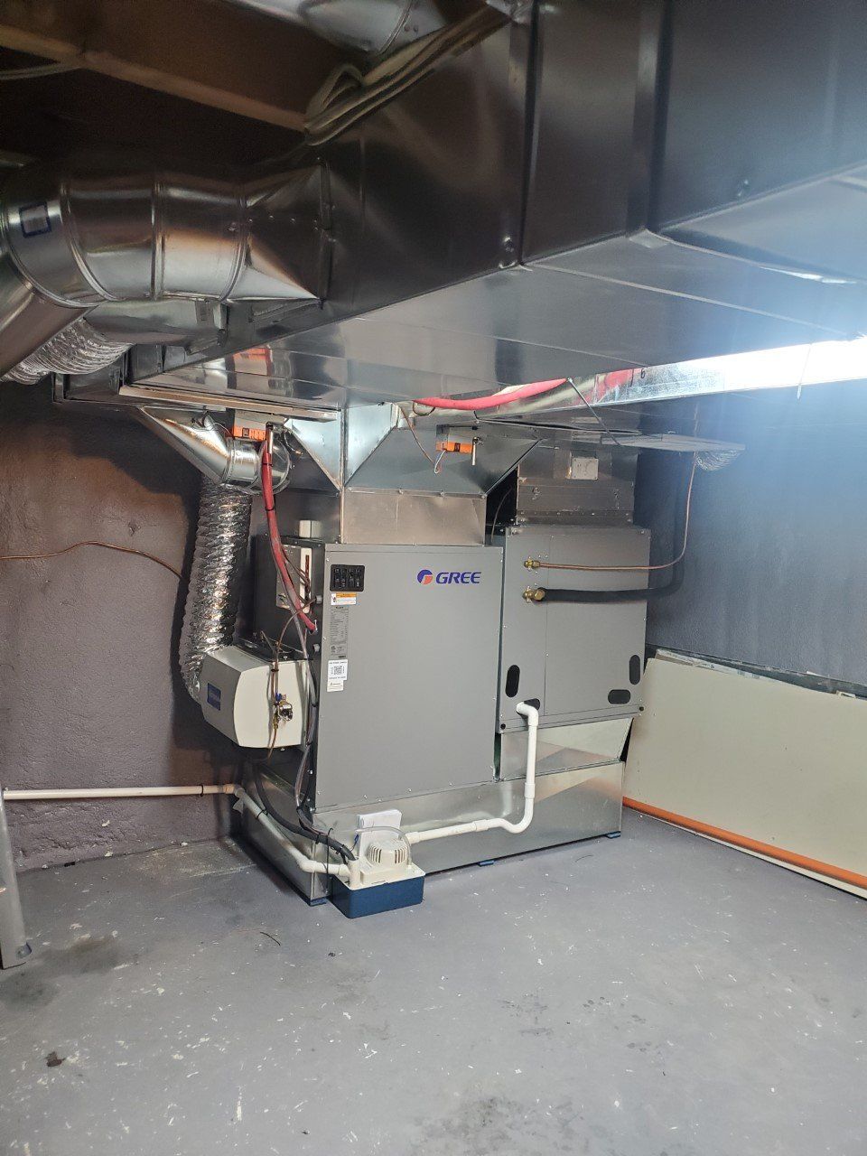 Un grand climatiseur est installé dans un sous-sol à côté d'un mur.