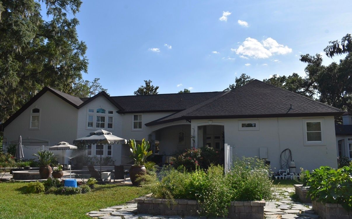 Suburban house with a garden, patio furniture, and a partly cloudy sky