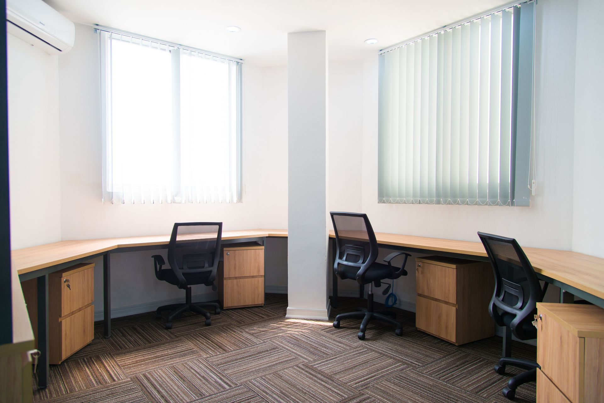 A small office with three desks and chairs in it.