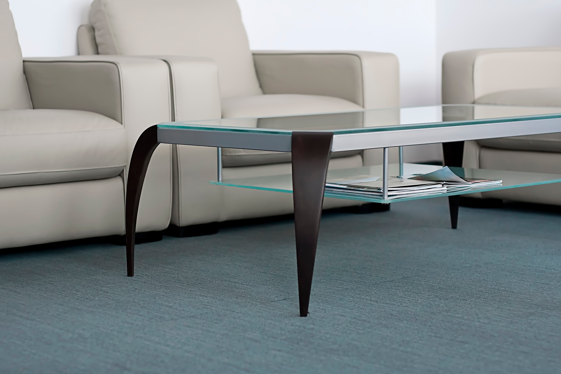 A glass coffee table in a living room with two chairs