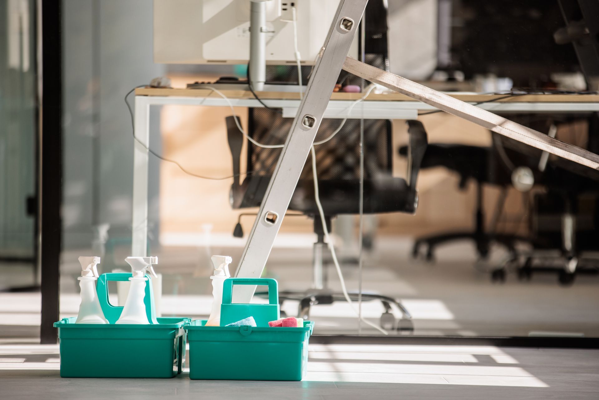 A cleaning caddy is sitting on the floor in an office next to a ladder.