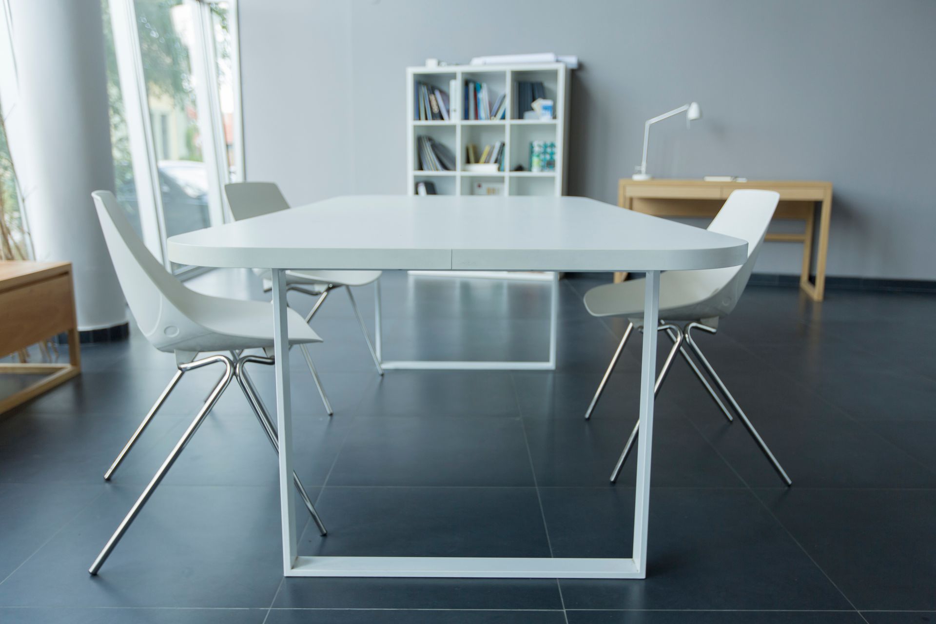 A white table and chairs in a room with a bookshelf in the background.