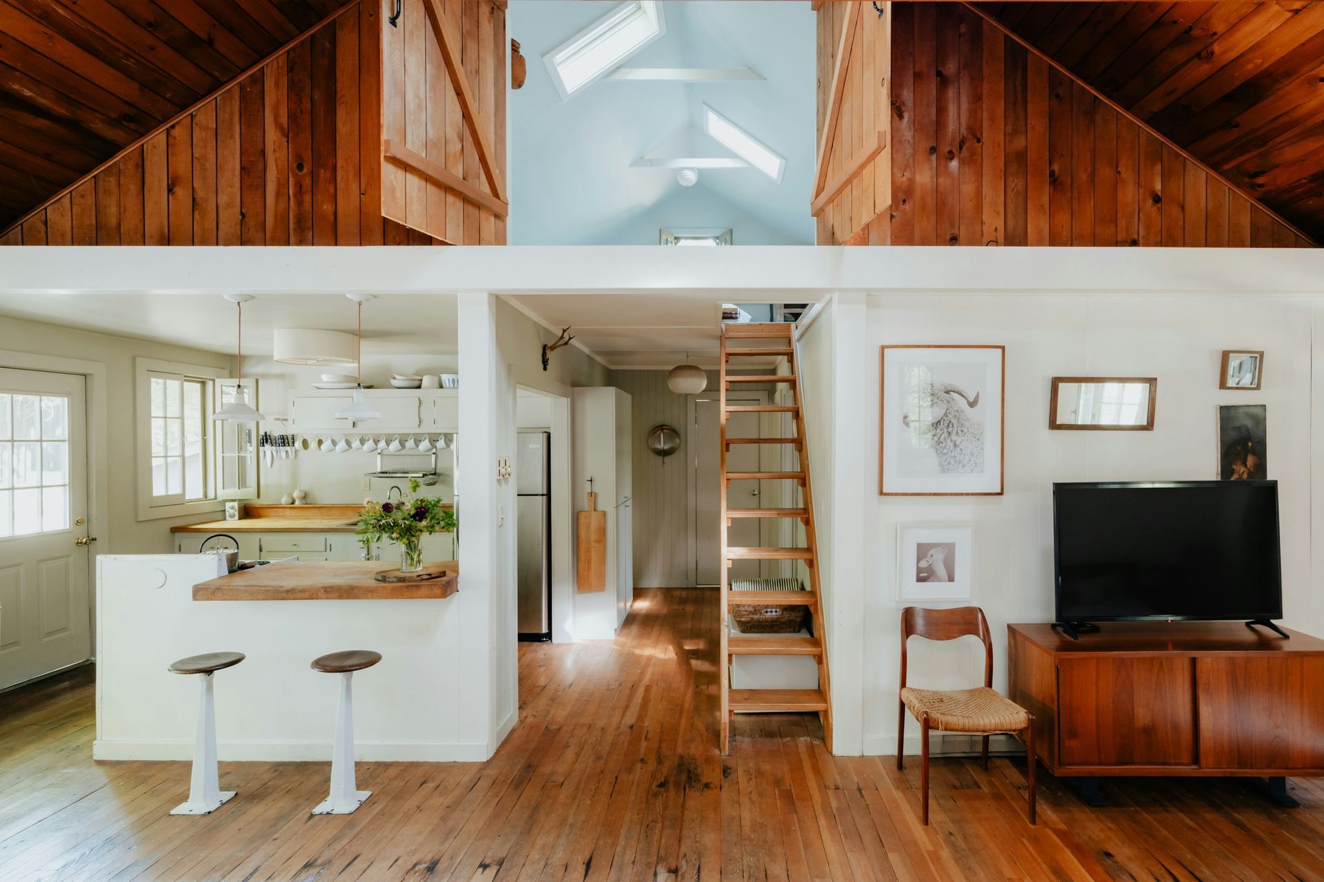 Interior of a white walled lake home with warm wooden flooring and kitchen island.