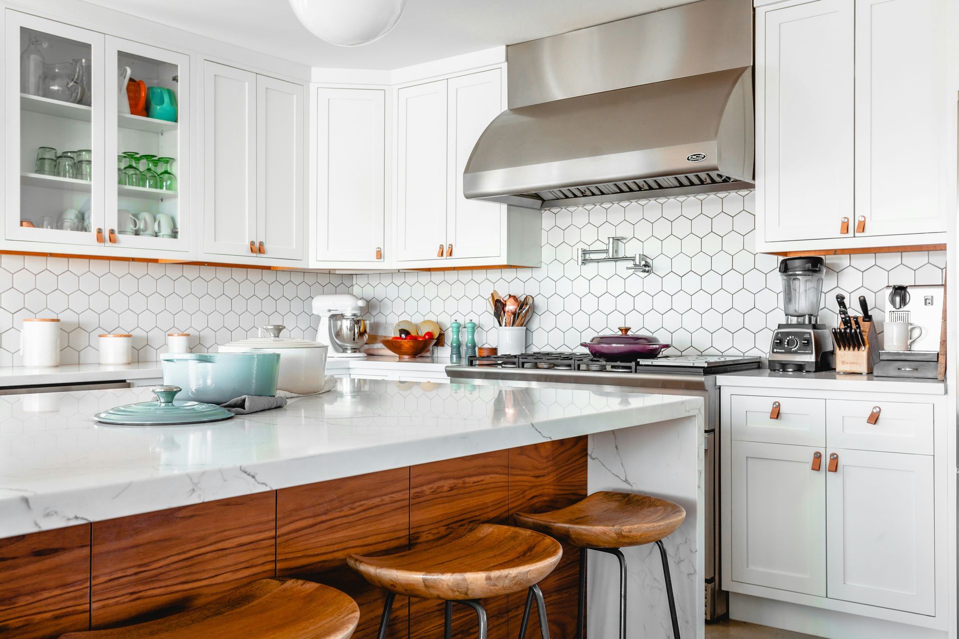 White kitchen with warm wooden drawers and bar stools.