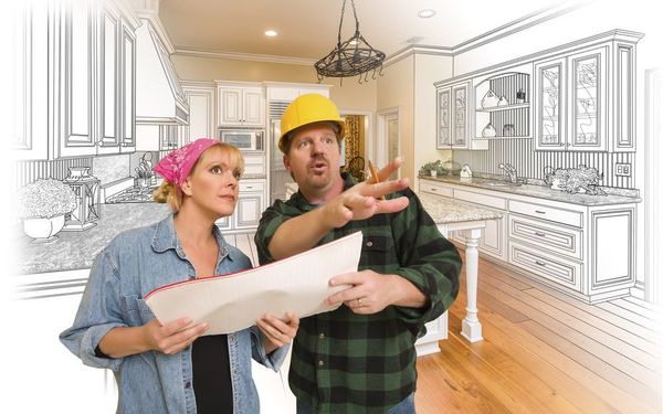 A man and a woman are looking at a blueprint of a kitchen.