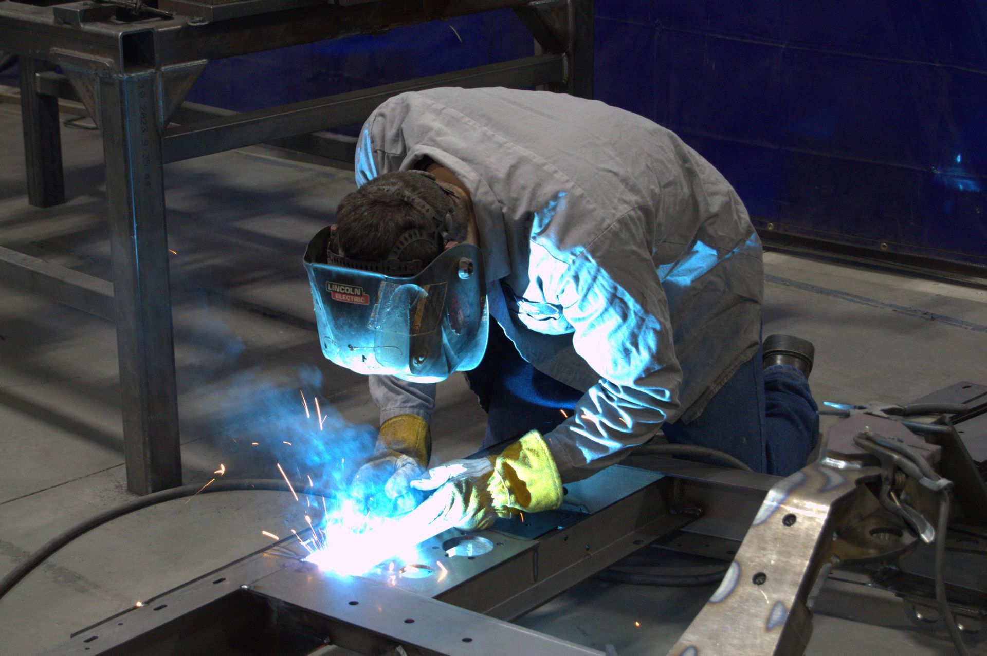 A man is welding a piece of metal in a factory.